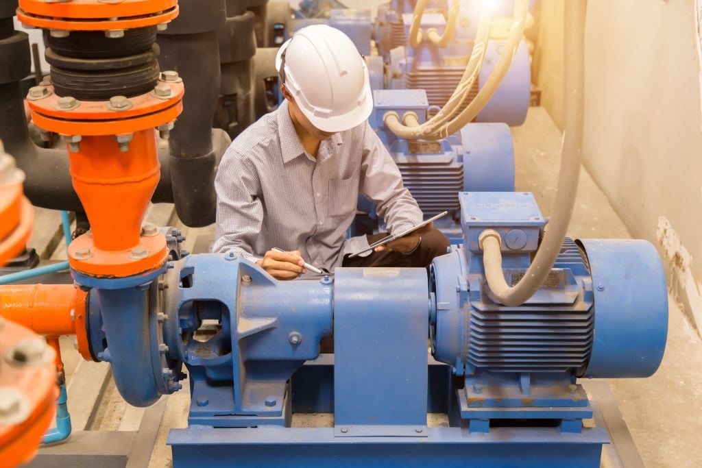 Plant operator conducting regular maintenance on industrial equipment